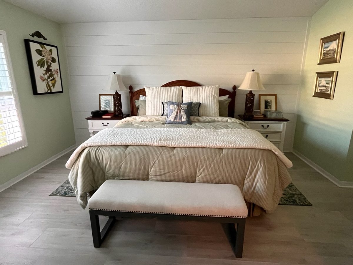 Bedroom after refresh with white shiplap accent wall and new flooring